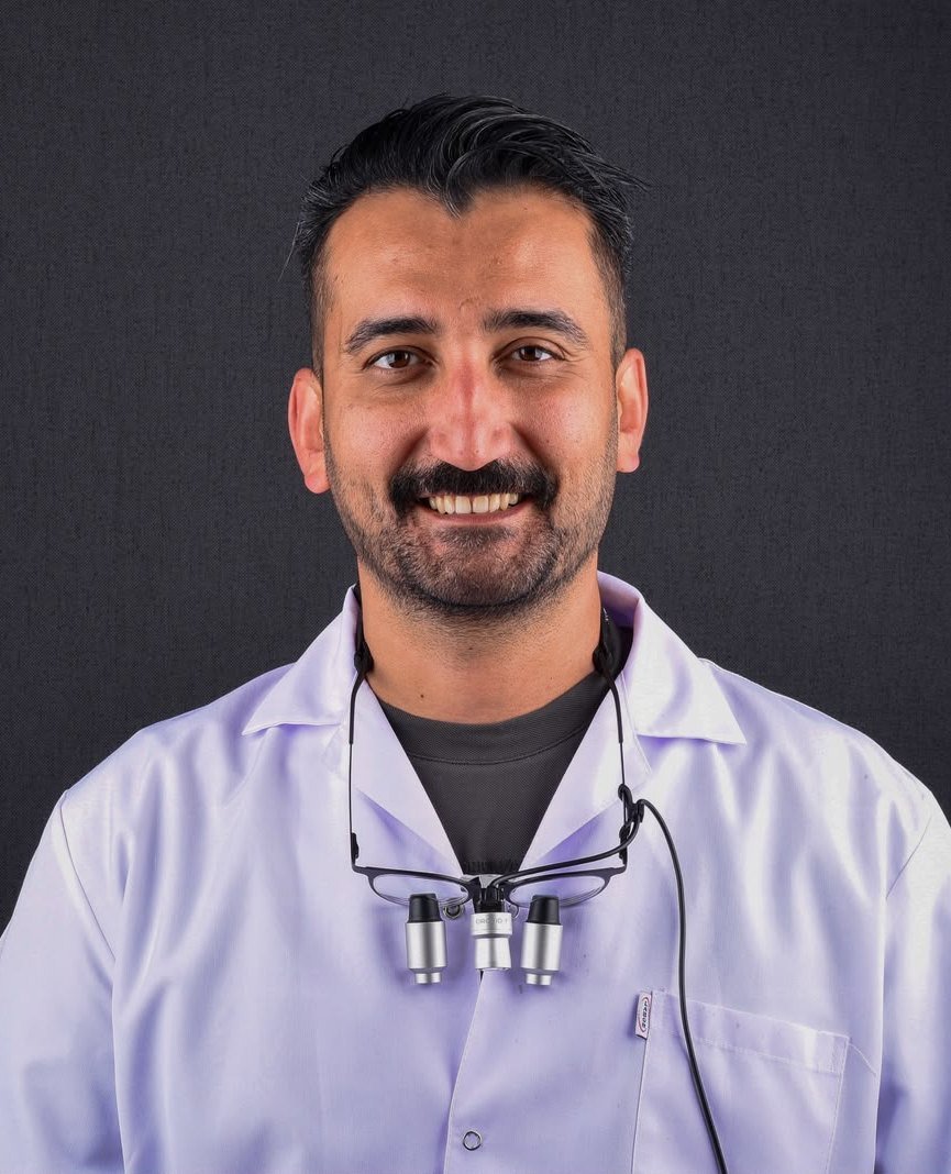 Dr. Dt. Mustafa Solmazgül, prosthodontist at Clinova Dental in Ankara, in a white clinic coat with dental loupes.